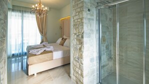 Un dormitorio con cama, ducha, paredes de piedra y un candelabro.