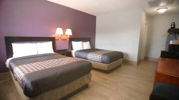 A hotel room with two beds, each with a headboard and bedside lamps.