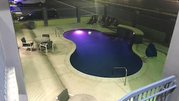 A swimming pool with a curved edge, surrounded by outdoor seating and a railing.