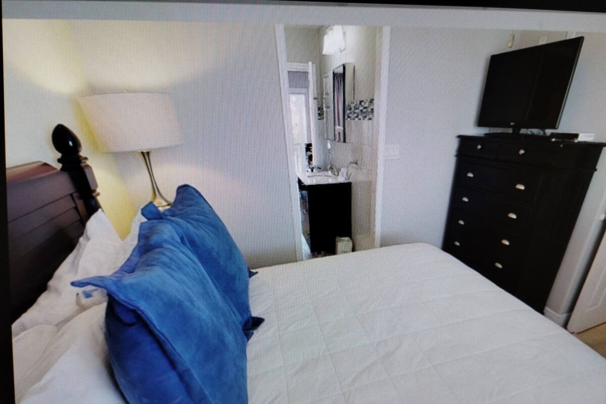 A hotel room with a bed, a dresser, a mirror, and a television.