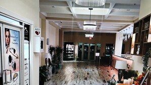 A hotel lobby with a wooden floor, a chandelier, a reception desk, and a sign indicating an AED. - Morritts Tortuga Club (East End)