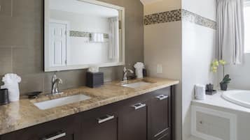 A modern bathroom with two sinks, a large mirror, and a bathtub.