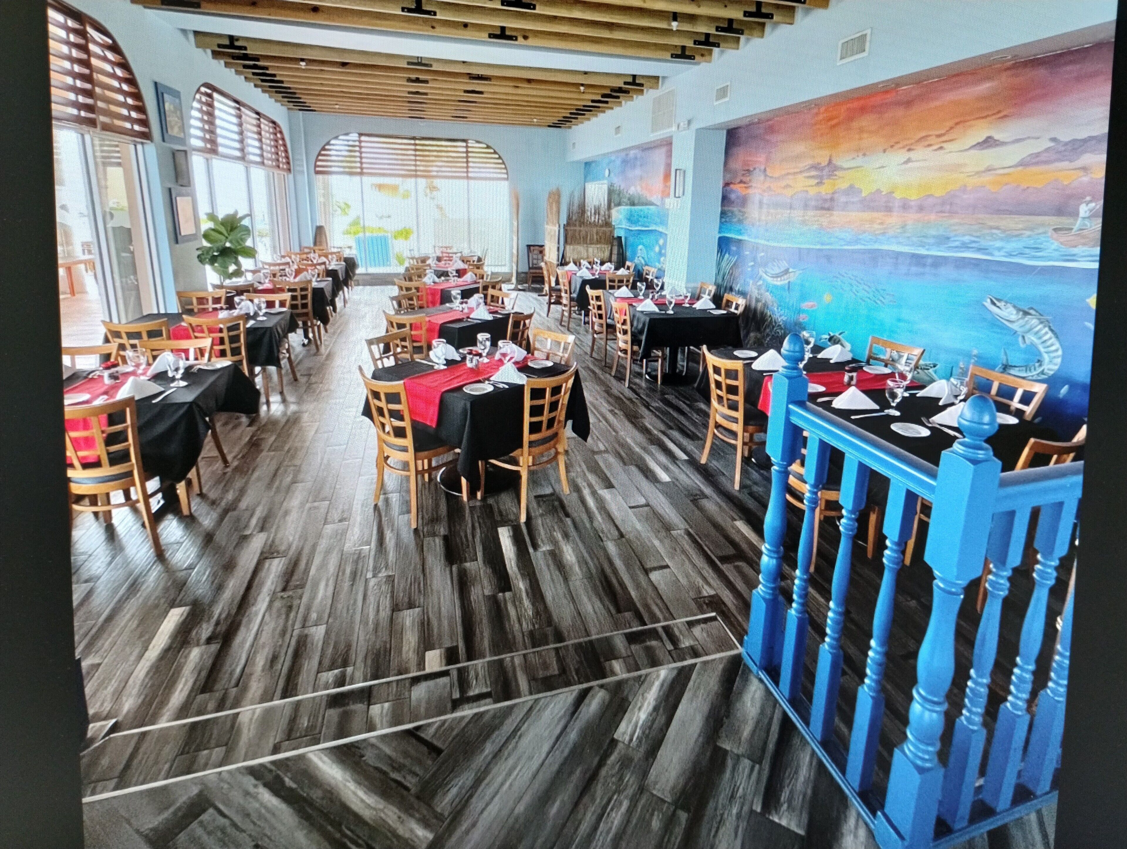 Un restaurant doté d'un plancher en bois, de tables recouvertes de nappes noires et de chaises.