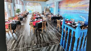 Un restaurant doté d'un plancher en bois, de tables recouvertes de nappes noires et de chaises.