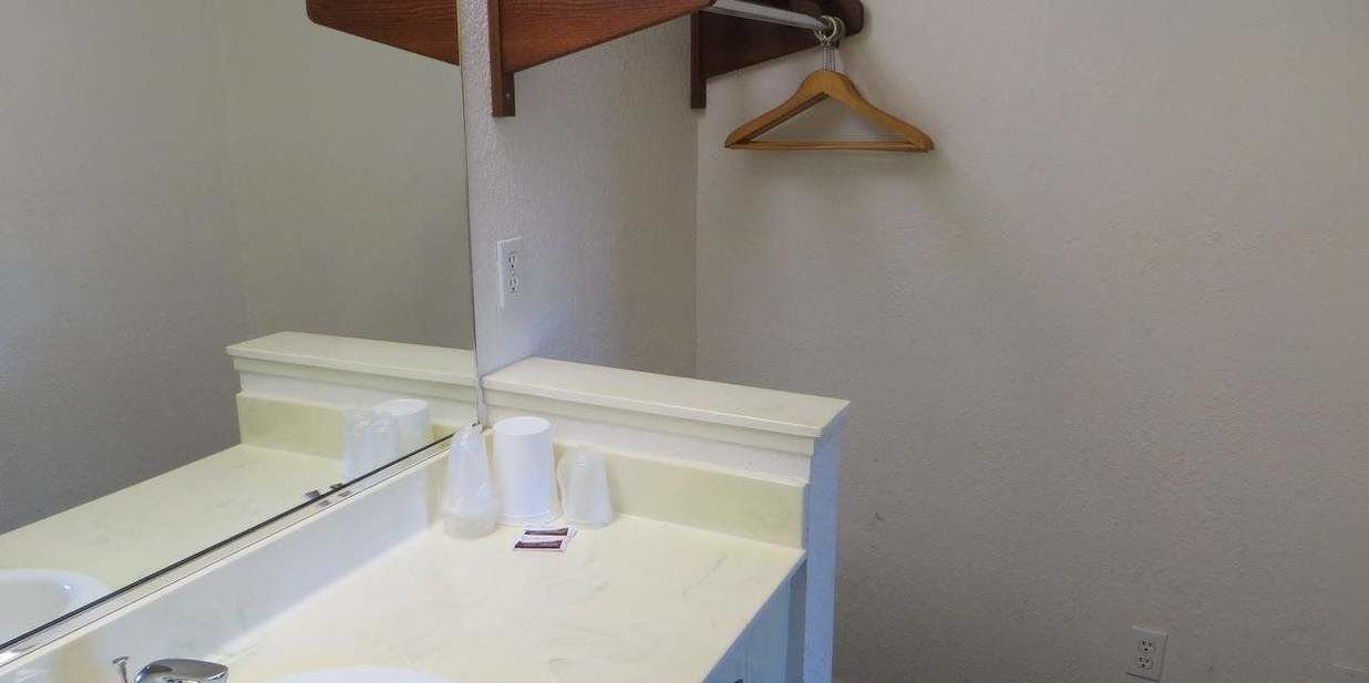 A bathroom with a white sink, mirror, and a wooden towel rack.
