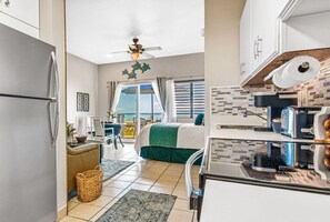 Enjoy a comfortable stay in this well-appointed room with a kitchenette, dining area, and seating space, featuring a bed and a large window with ocean views.