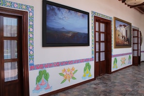 Un corridoio con porte in legno, decorazioni murali colorate e quadri appesi.