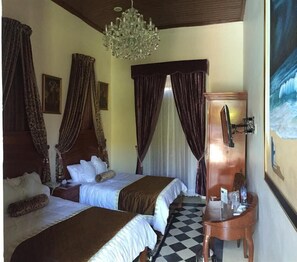 A hotel room with two beds, a chandelier, a checkered floor, and a painting on the wall. - Hotel La Casa del Marques de Comillas (Comitan de Dominguez)