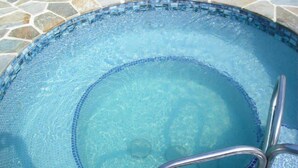 A clear blue pool with a stone tiled edge and a metal ladder. - Sea Ge 1-203 1 Bedroom Condo by RedAwning (Kailua-Kona)