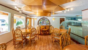 A restaurant with a wooden ceiling, round tables, and wicker chairs. - Hotel Hacienda Montesinos (Morelia)