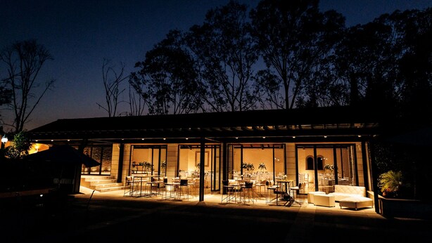 A modern building with a glass facade, outdoor seating area, and a well-lit interior. - Hotel Hacienda Montesinos (Morelia)