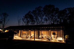 Un edificio moderno con fachada de vidrio, zona de estar al aire libre e interior bien iluminado.