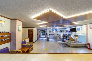 Um saguão de hotel com balcão de recepção, área de estar e uma pequena loja.