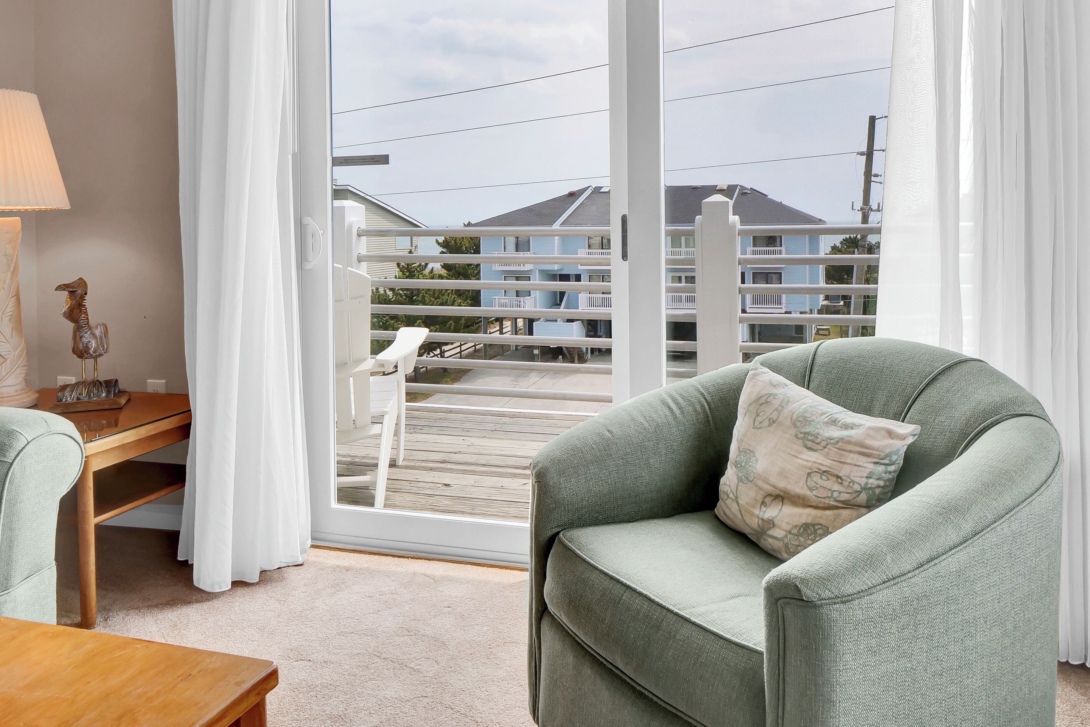 Een balkon met een witte reling, een houten terras en uitzicht op een gebouw met meerdere balkons.