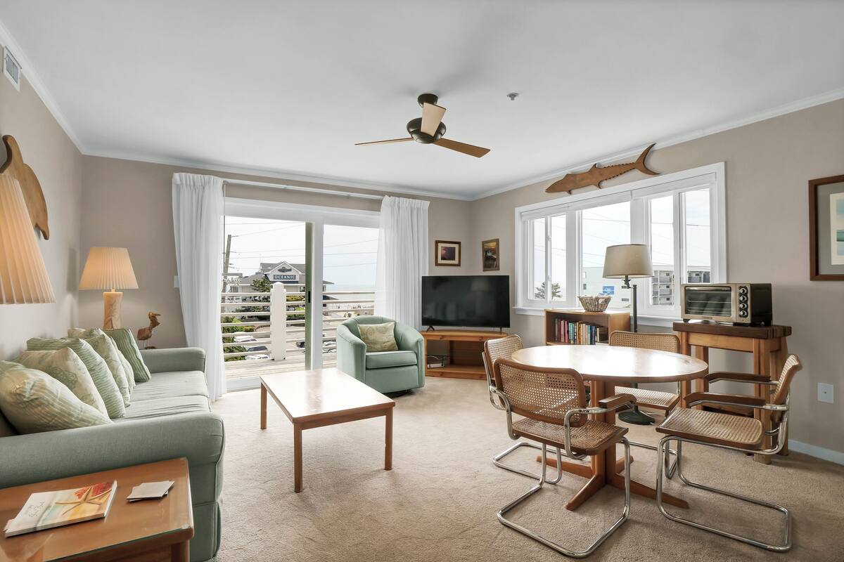 Un salon comprenant un canapé, une table basse, une table à manger avec des chaises, un téléviseur et un ventilateur de plafond.