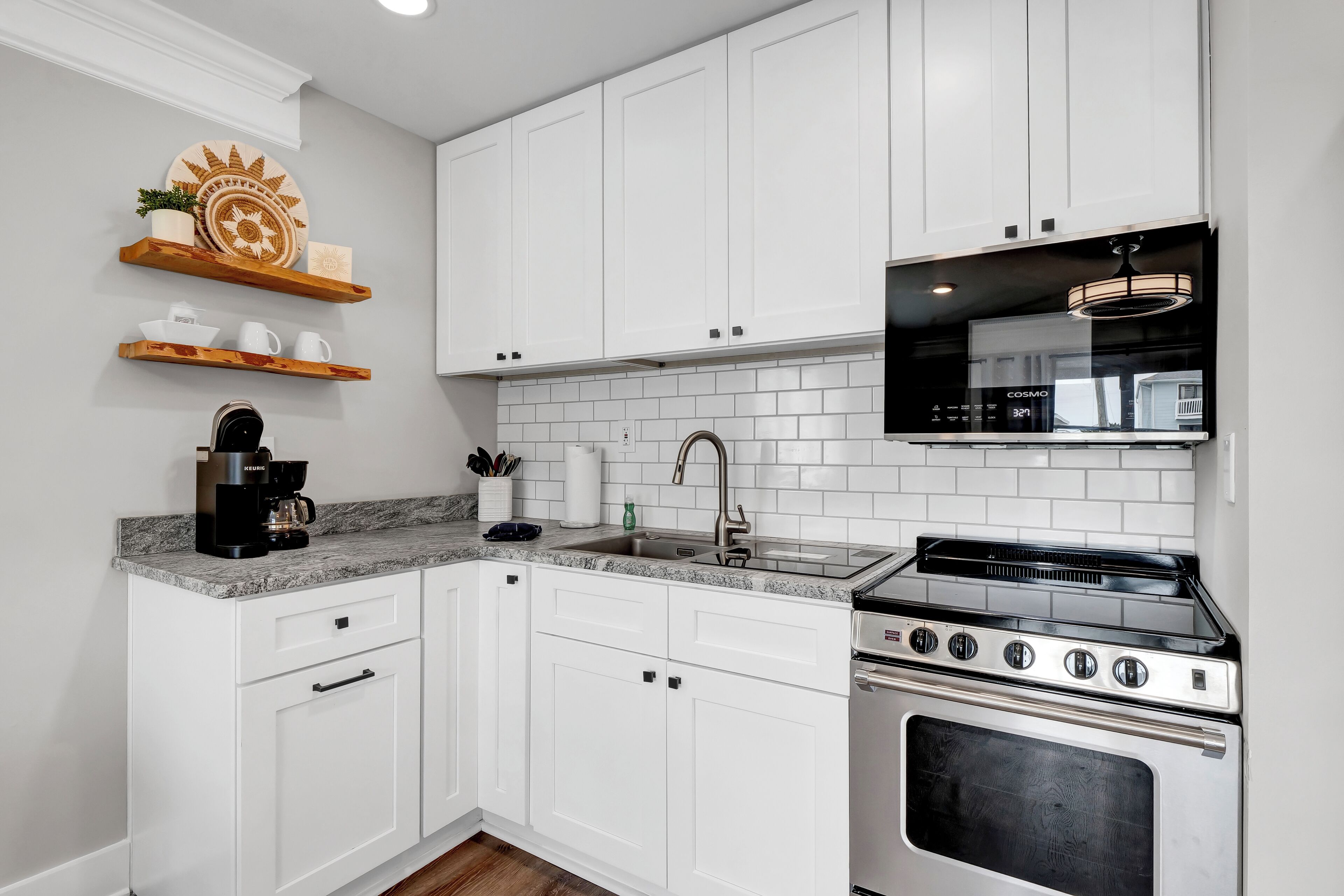 A modern kitchen with white cabinets, a granite countertop, a stainless steel stove, and a built-in microwave.