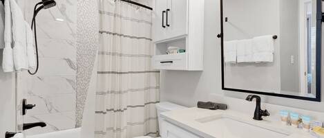 A modern bathroom with a bathtub, toilet, and vanity with a mirror.