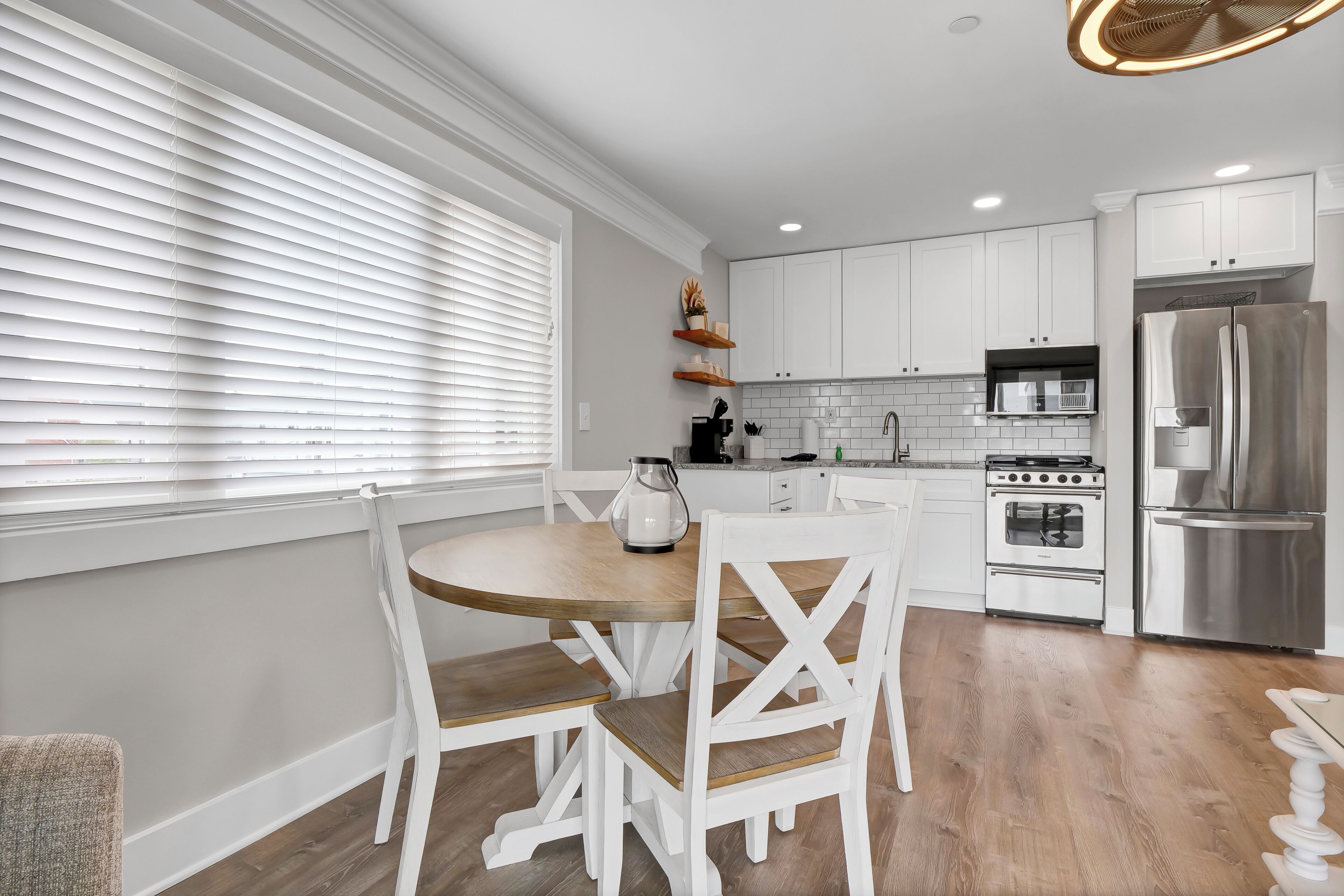 A modern kitchen with white cabinetry, a wooden dining table, and a built-in oven.
