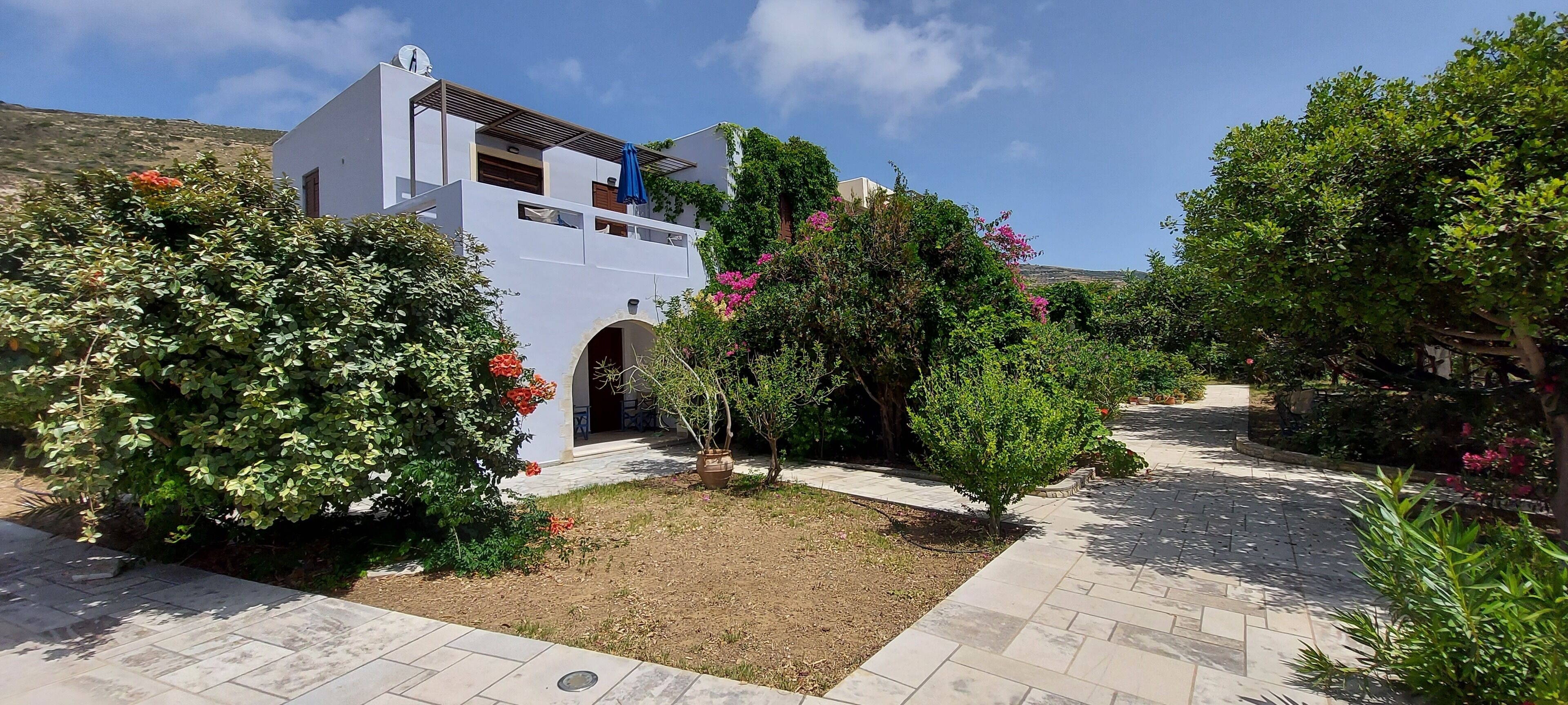 A modern white building with a covered outdoor area and a paved pathway.