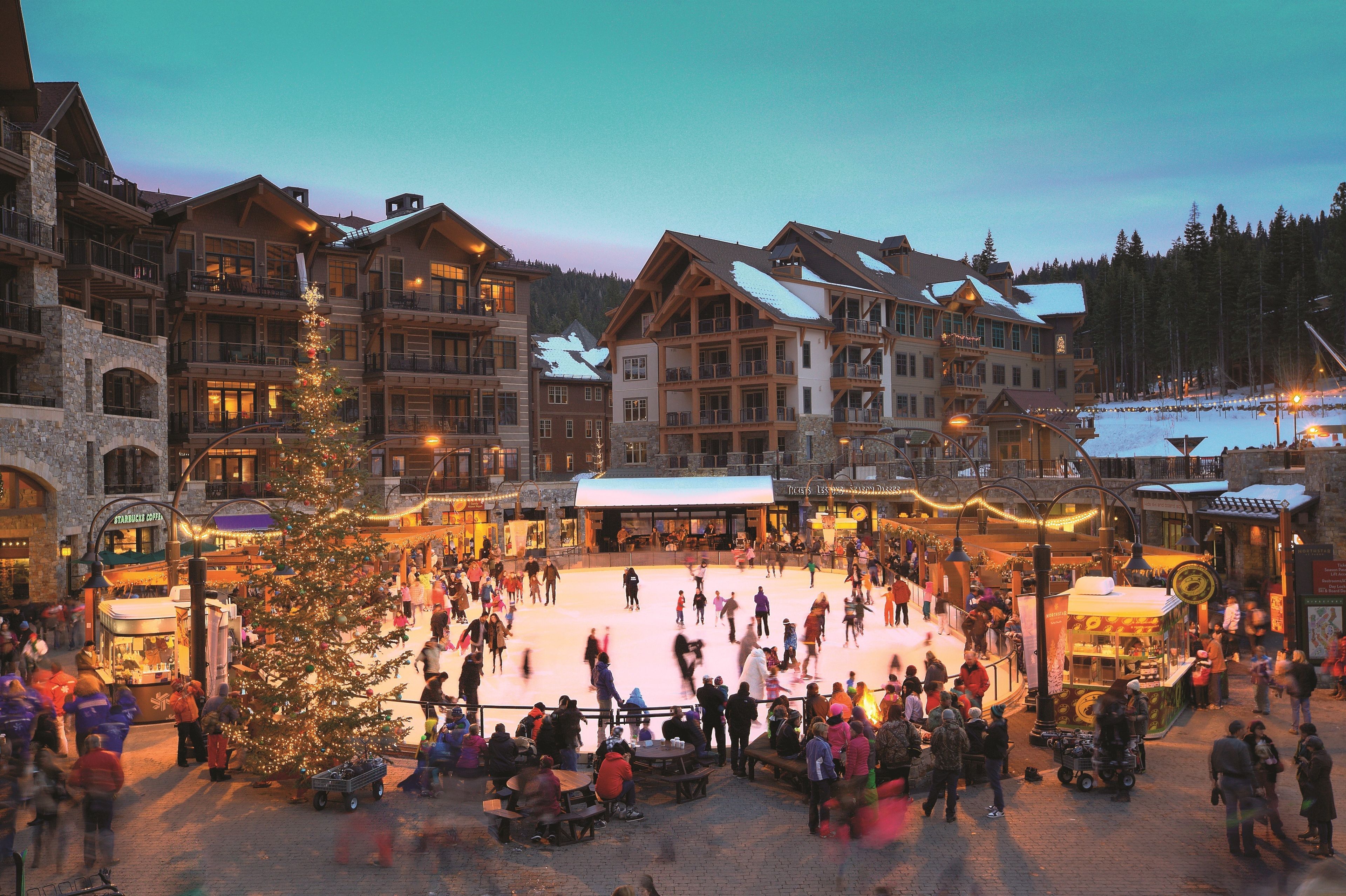 A large indoor ice skating rink surrounded by multi-story buildings with balconies.