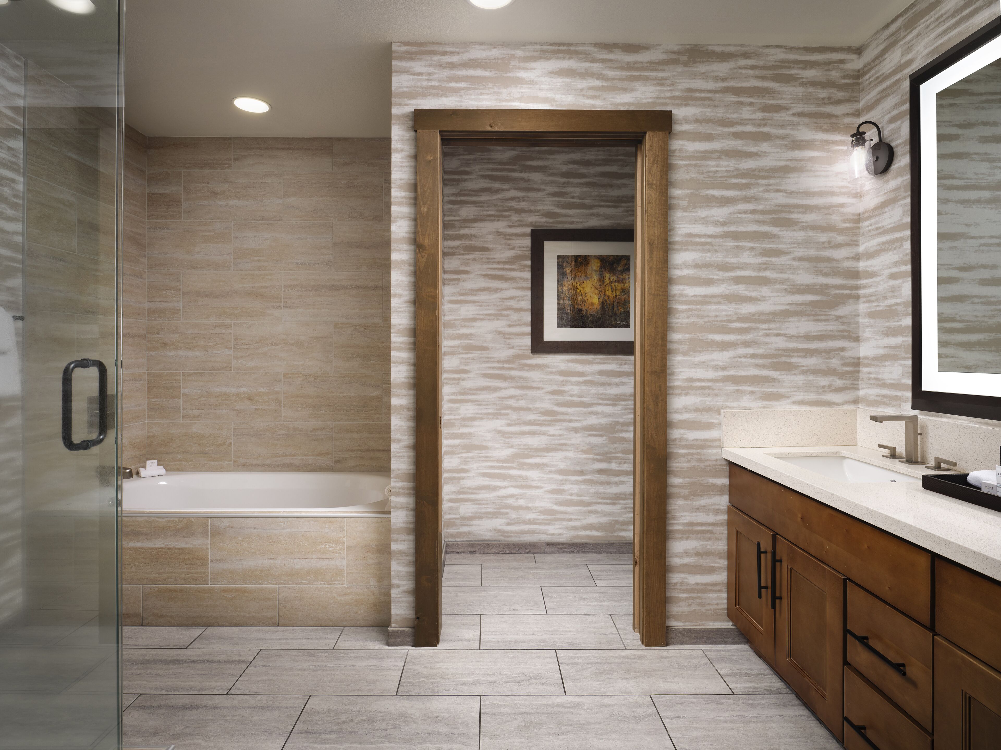 Une salle de bain moderne dotée d’une douche à parois de verre, d’une baignoire sur pieds et de meubles en bois.