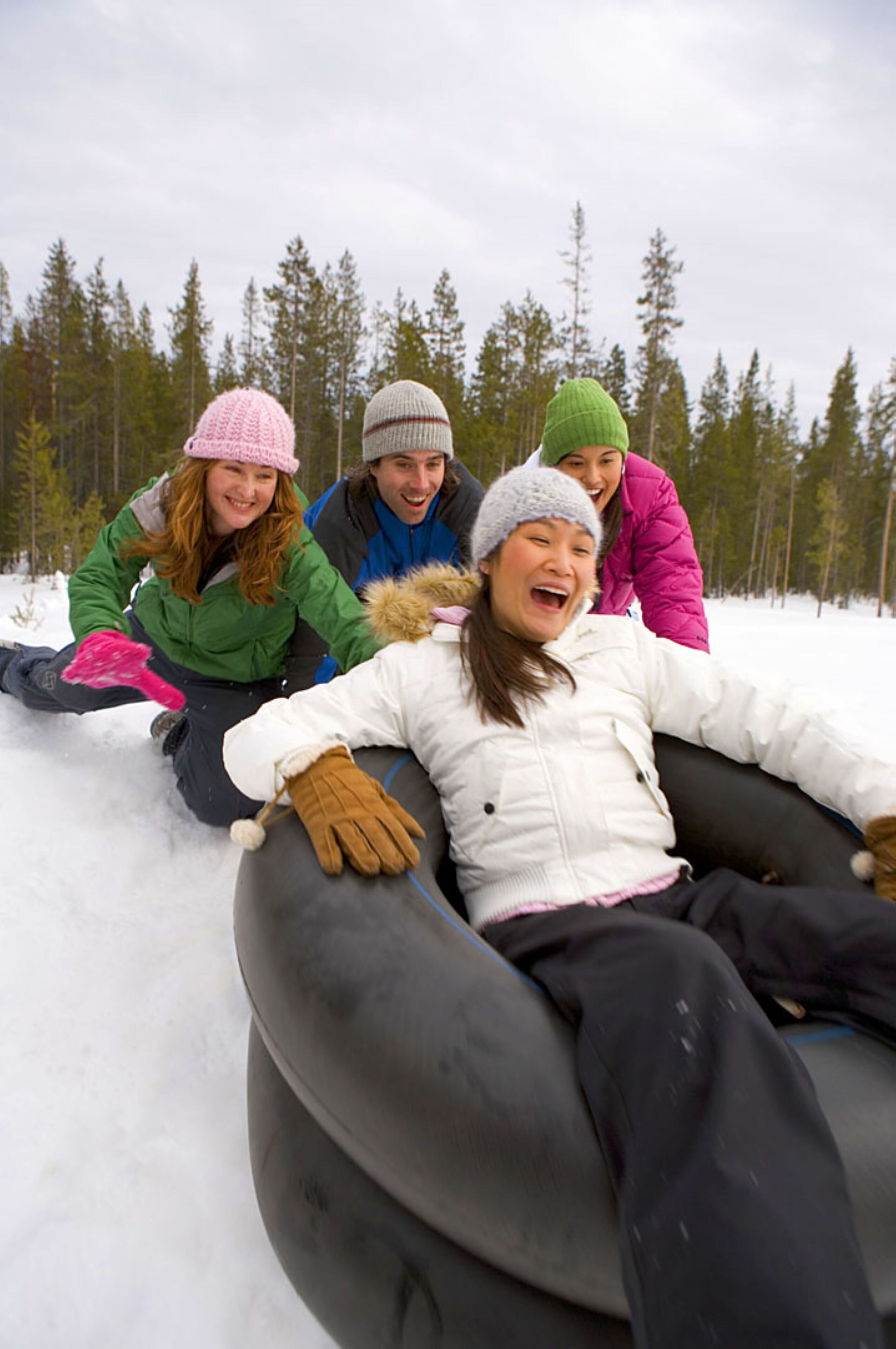 A group of people sledding in a snowy outdoor setting.