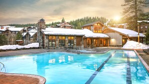 Un resort con piscina, edificios de piedra y tejados cubiertos de nieve.