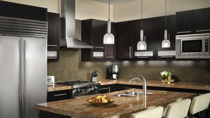 Una cocina moderna con armarios oscuros, electrodomésticos de acero inoxidable, encimera de granito y una isla central con taburetes de bar.