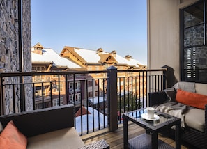 Enjoy the serene view from this cozy balcony with a sofa, table, and chair.