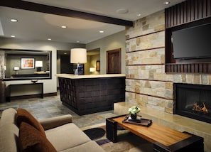 Cozy living space with a fireplace, comfortable sofa, and a desk area.