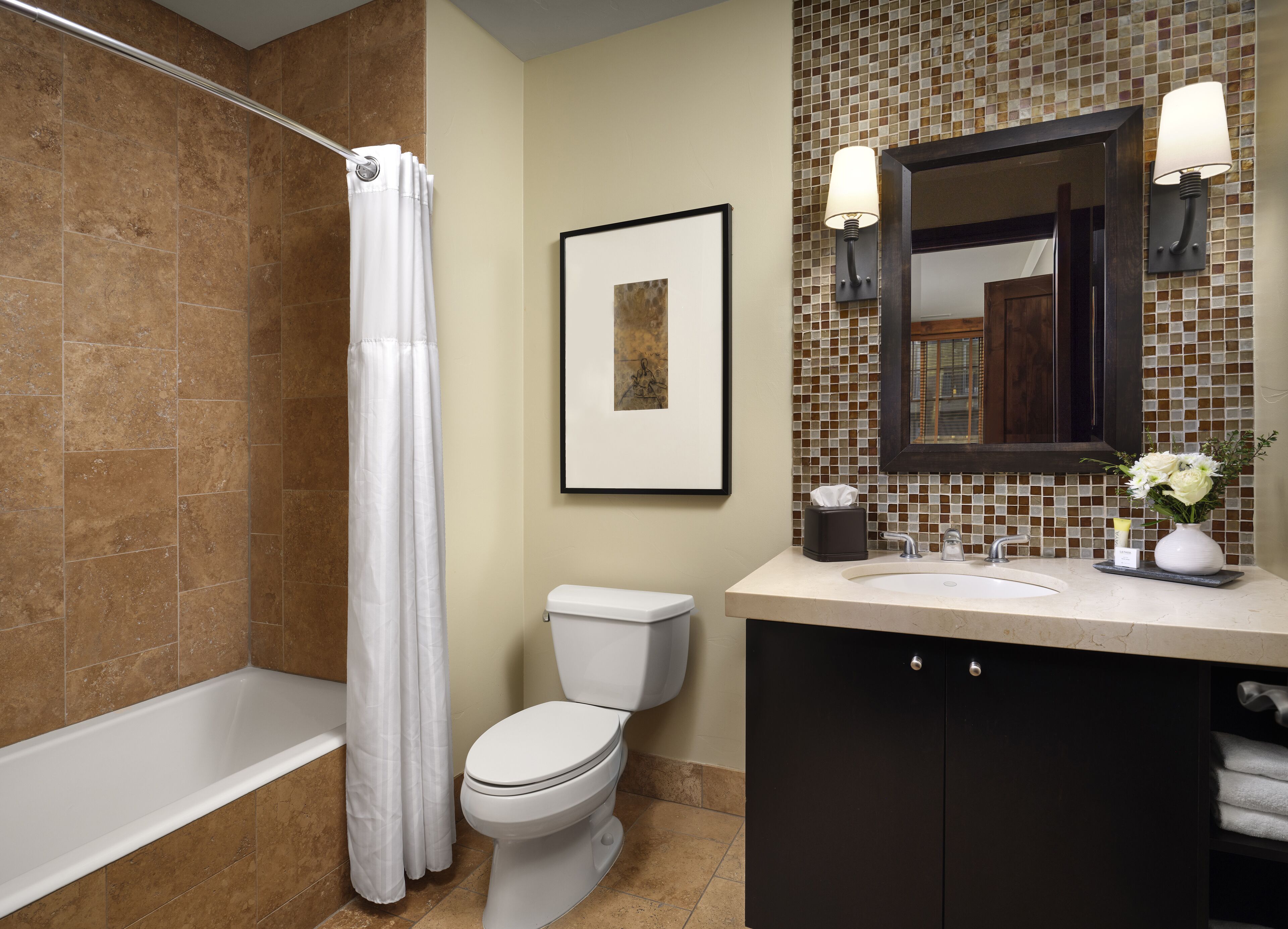 A bathroom with a shower, toilet, sink, and mirror.