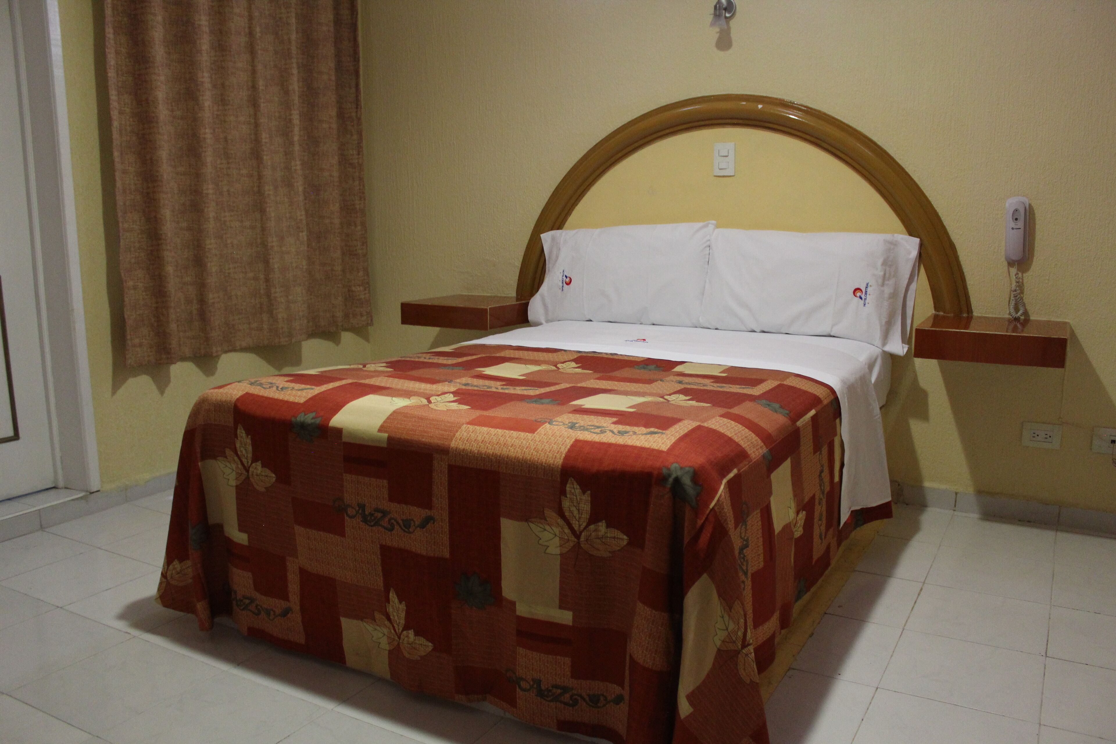 Una cama con colcha de estampado floral, cabecera de madera y mesitas de noche con lámparas.