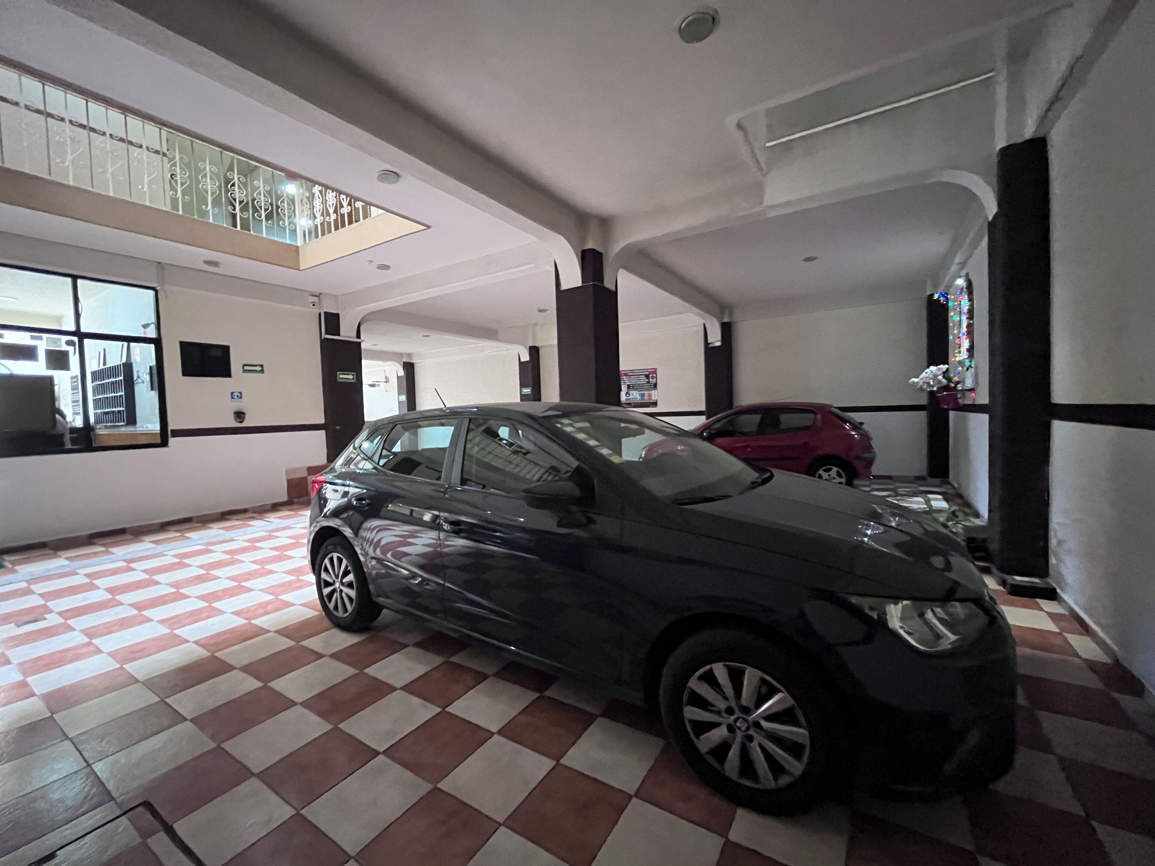 Un estacionamiento con un coche negro estacionado al frente.