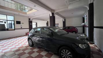 Un estacionamiento con un coche negro estacionado al frente.