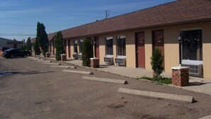 A row of motel rooms with individual doors, air conditioning units, and small brick planters. - Ivanhoe Motel (Lloydminster)