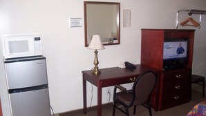 A hotel room with a kitchenette, a desk with a chair, a television, and a mirror. - Ivanhoe Motel (Lloydminster)