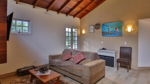 A spacious living room with a high wooden ceiling, a sofa, a coffee table, and a painting on the wall. - Villa Belle Chalés (Campos do Jordão)