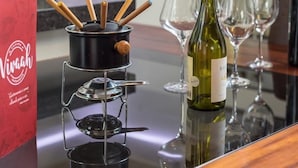 A modern kitchen with a portable stove, wine bottle, and glasses on a reflective surface. - Villa Belle Chalés (Campos do Jordão)
