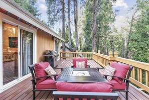 An outdoor deck with a table and chairs, surrounded by a wooden railing and trees. - Lake Arrowhead - Dreamin' 3 Bedroom Home by RedAwning (Cedar Glen)