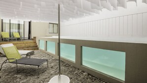 A modern hotel lobby with a brick floor, a high ceiling with geometric patterns, a glass partition, and a seating area with yellow and black chairs. - Marcel de Buenos Aires (Buenos Aires)