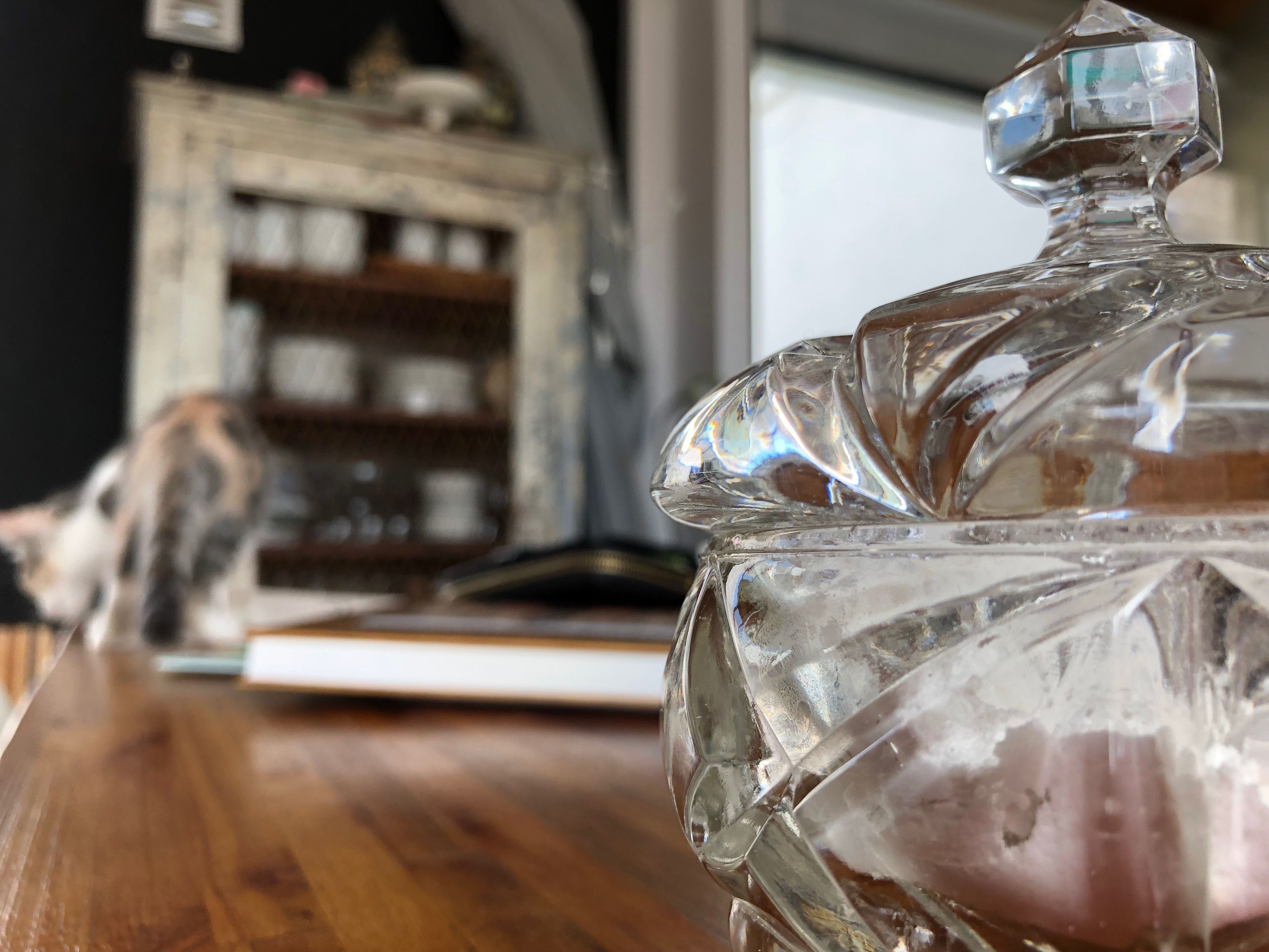 A clear glass bottle with a stopper on a wooden surface.