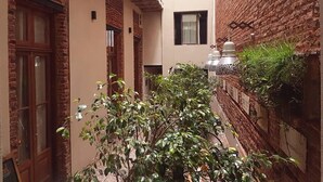 A narrow alleyway with brick walls, a wooden door, and a small balcony. - Marcel de Buenos Aires (Buenos Aires)