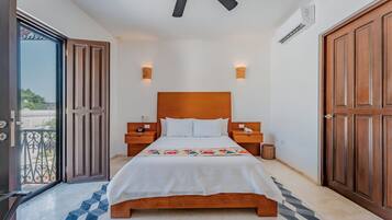 A bedroom with a wooden bed, two bedside tables, a ceiling fan, and a view through an open door.