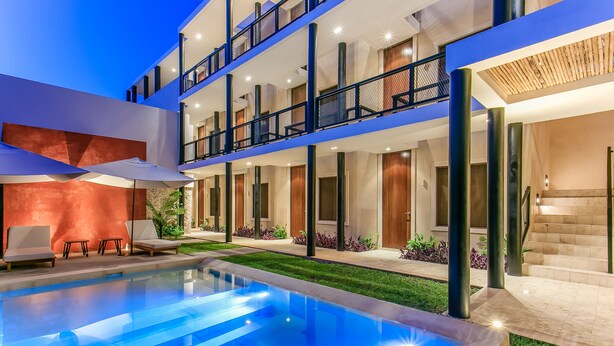 A modern hotel with a pool, outdoor seating, and a well-lit balcony area. - Casona 61 Boutique Hotel (Mérida)