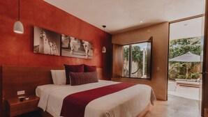 A bedroom with a large bed, a nightstand, a red accent wall, and a window with a view of the outdoors. - Casona 61 Boutique Hotel (Mérida)