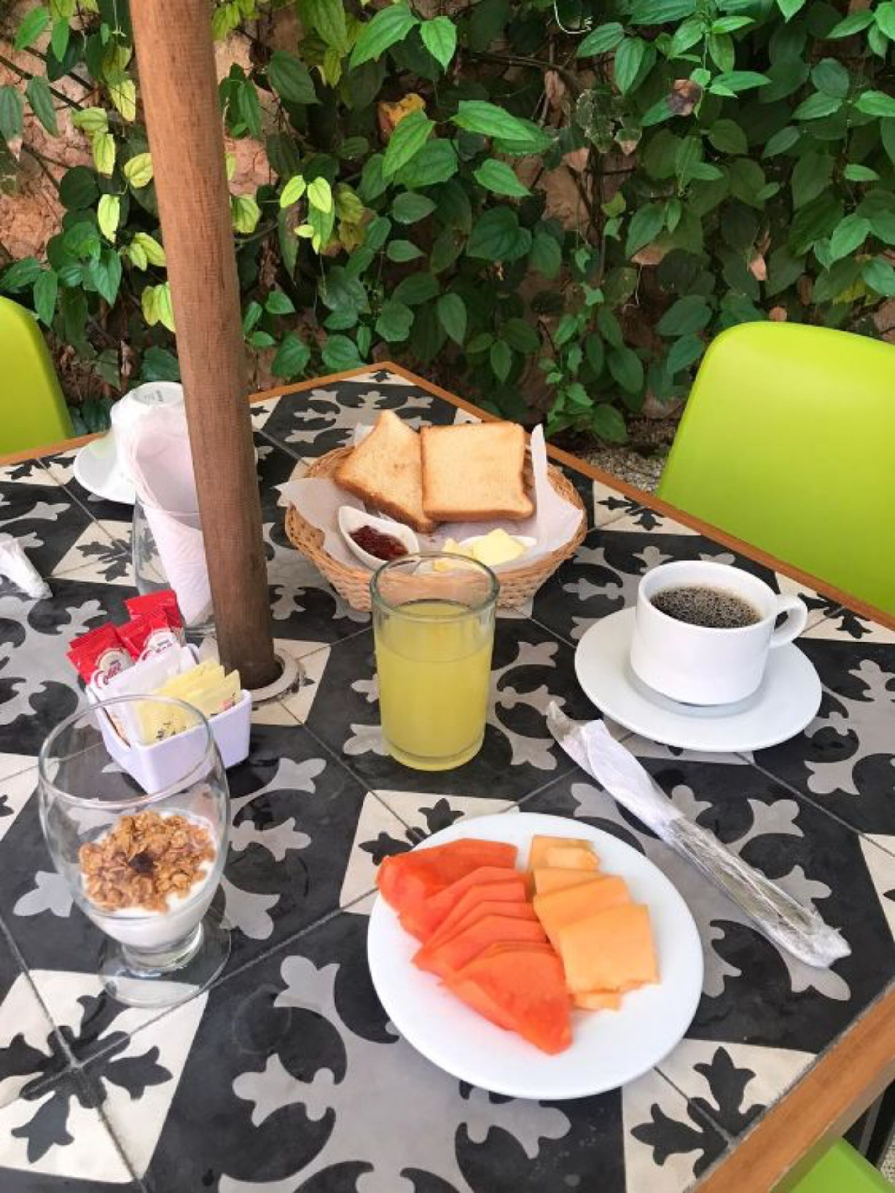 Una mesa preparada para el desayuno, con tostadas, jugo, café y fruta.