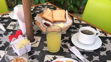 Una mesa preparada para el desayuno, con tostadas, jugo, café y fruta.
