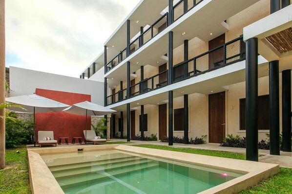 A modern multi-story building with a pool area, outdoor seating, and a covered patio. - Casona 61 Boutique Hotel (Mérida)