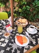 Una mesa servida con alimentos para el desayuno, incluyendo tostadas, fruta, un vaso de jugo y una taza de café.