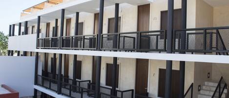 A multi-story building with balconies, staircases, and a flat roof.